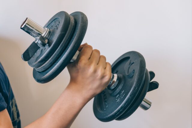 young lifting weights at the gym with space for copy t KElOV